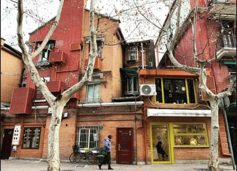 Maison en briques rouges et platanes dans une rue de la Concession française