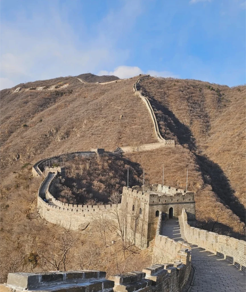 Grande Muraille de Chine serpentant sur des collines arides avec une tour de guet